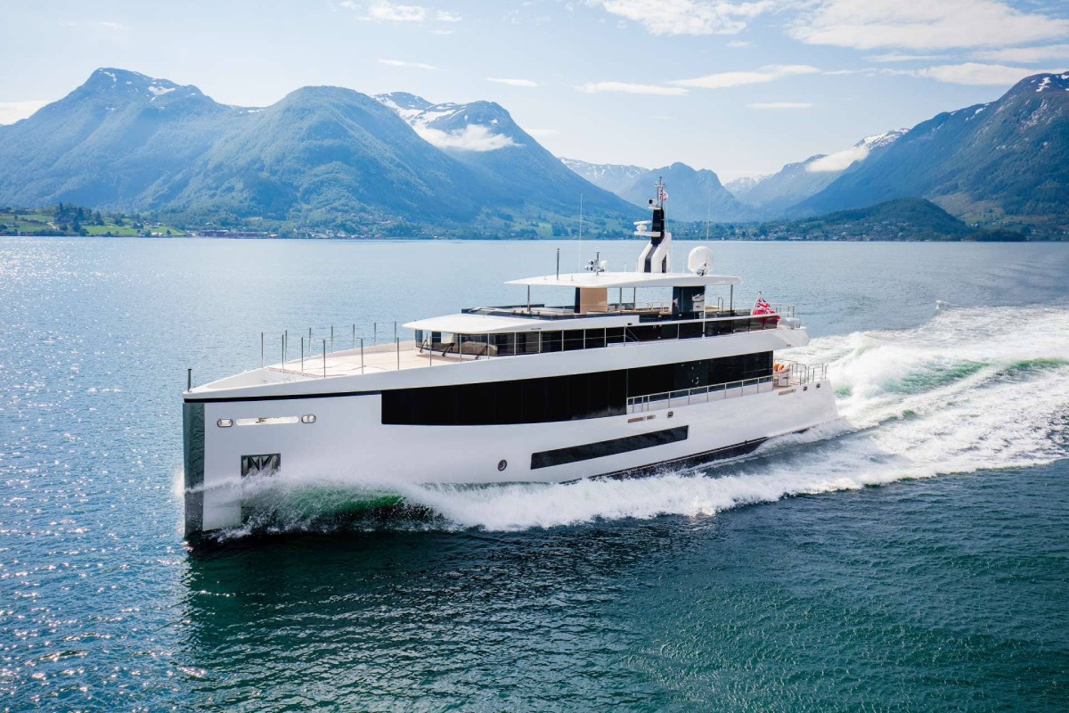 Yacht di lusso Feadship naviga in un mare calmo circondato da montagne verdi. L'imbarcazione su misura è un esempio di tecnologia avanzata e design elegante, riflettendo l'eccellenza del cantiere navale olandese Feadship.