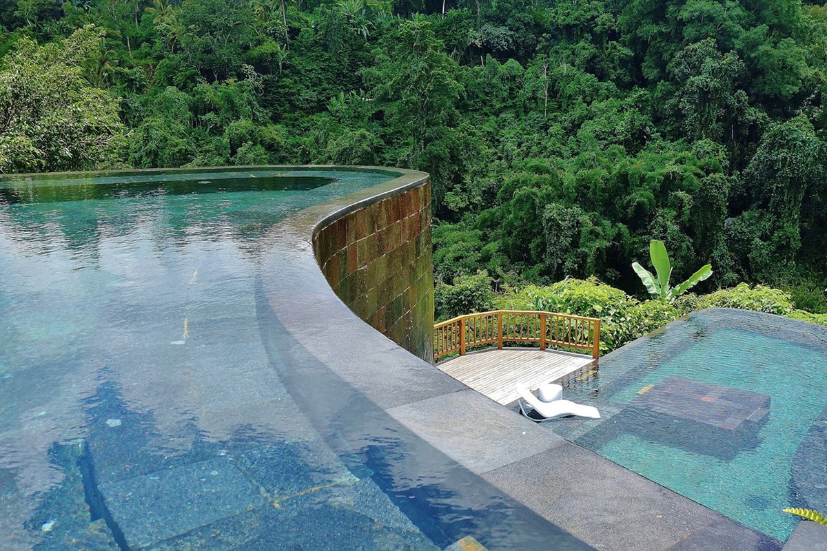 Piscina a sfioro in una villa di lusso circondata da un giardino tropicale con vista panoramica sulla foresta.